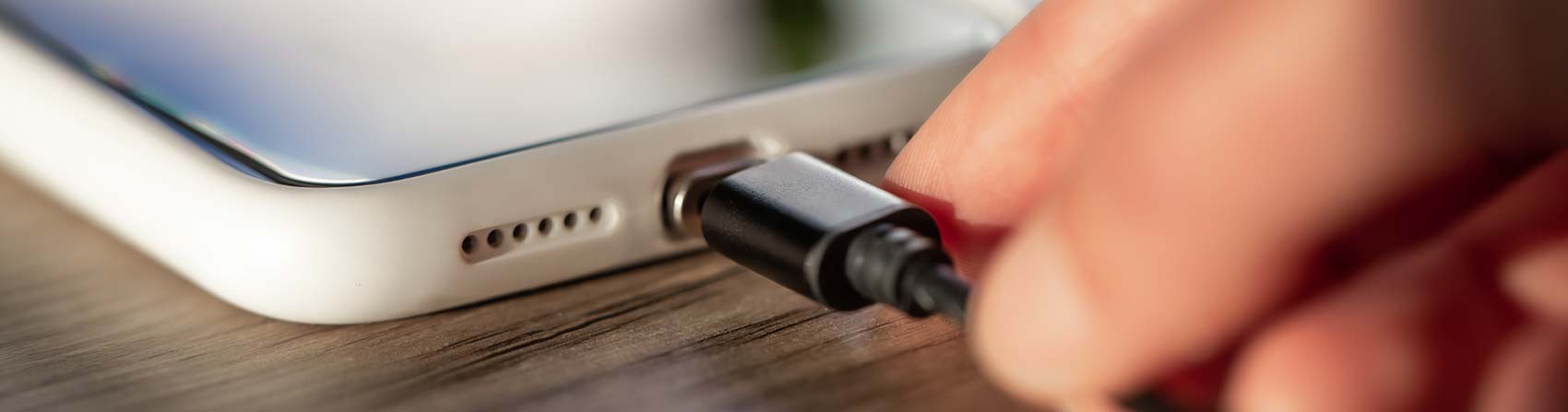 A person plugging a charging cable into a smartphone, highlighting Qualcomm Quick Charge technology for fast and efficient device charging.